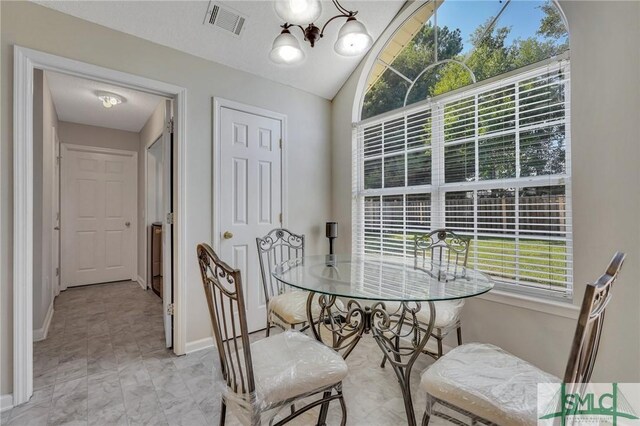 tiled dining room with an inviting chandelier and lofted ceiling