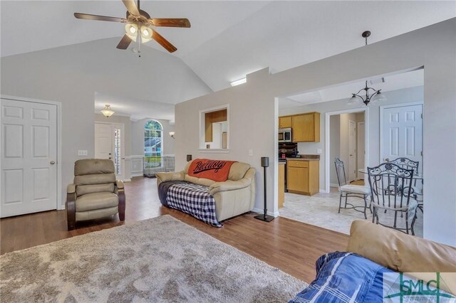 living room featuring ceiling fan, light hardwood / wood-style flooring, and vaulted ceiling