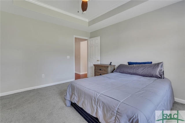 bedroom featuring ceiling fan, crown molding, a tray ceiling, and carpet floors