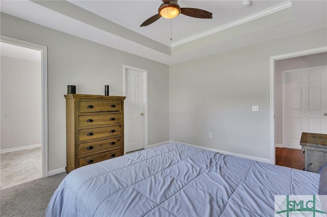 bedroom with ceiling fan, a tray ceiling, and carpet