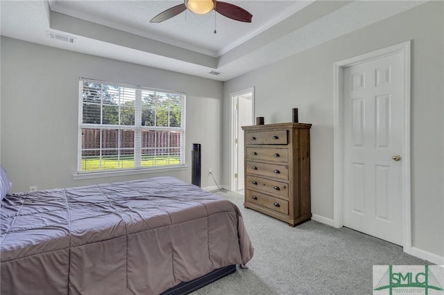 carpeted bedroom featuring ceiling fan, ornamental molding, and a raised ceiling