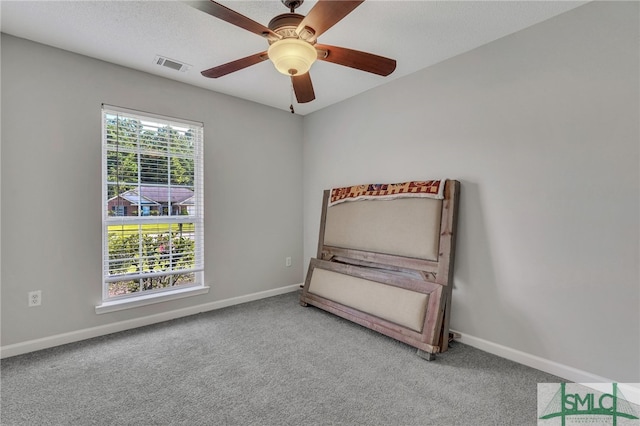 unfurnished bedroom with ceiling fan, a textured ceiling, multiple windows, and carpet floors