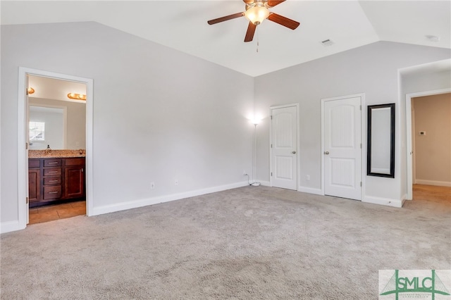 unfurnished bedroom with ceiling fan, ensuite bath, lofted ceiling, and light colored carpet