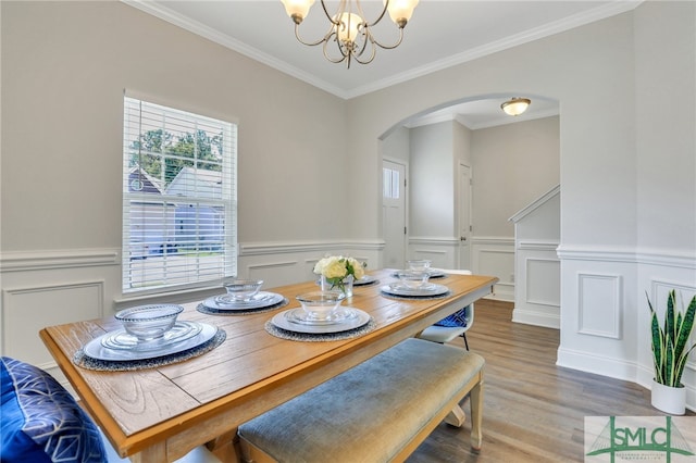 dining space featuring crown molding, hardwood / wood-style flooring, and an inviting chandelier