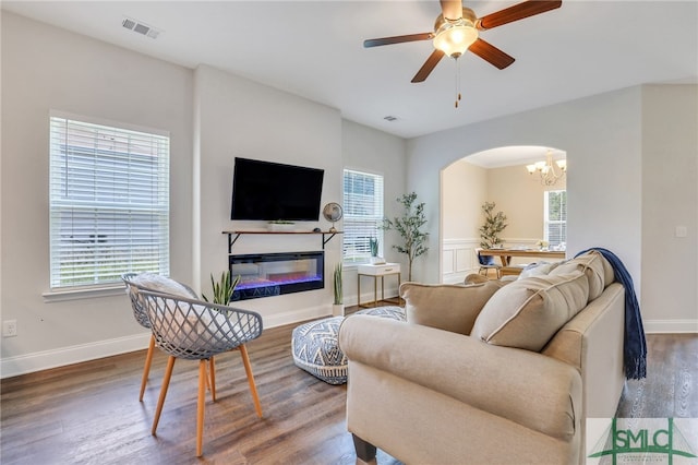 living room with ceiling fan with notable chandelier and hardwood / wood-style floors