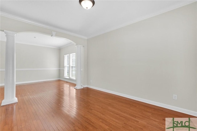 empty room with decorative columns, crown molding, and wood-type flooring