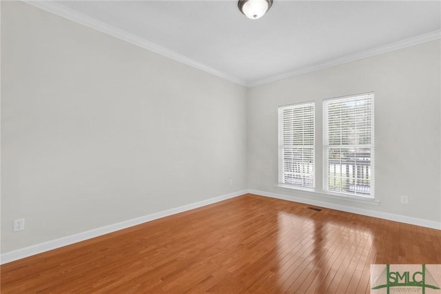 empty room featuring hardwood / wood-style floors and crown molding