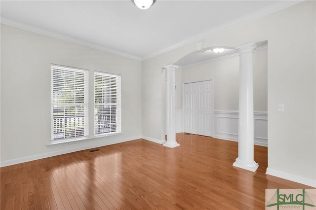 spare room with decorative columns, ornamental molding, and hardwood / wood-style flooring