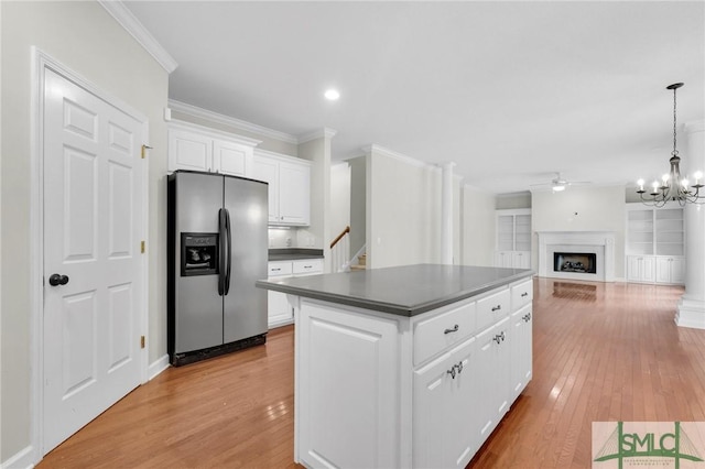 kitchen featuring white cabinets, hanging light fixtures, stainless steel fridge, and light hardwood / wood-style flooring