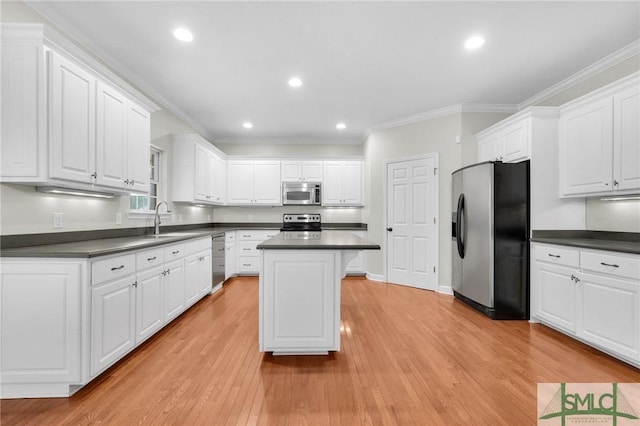 kitchen featuring light hardwood / wood-style flooring, stainless steel appliances, white cabinets, a kitchen island, and ornamental molding