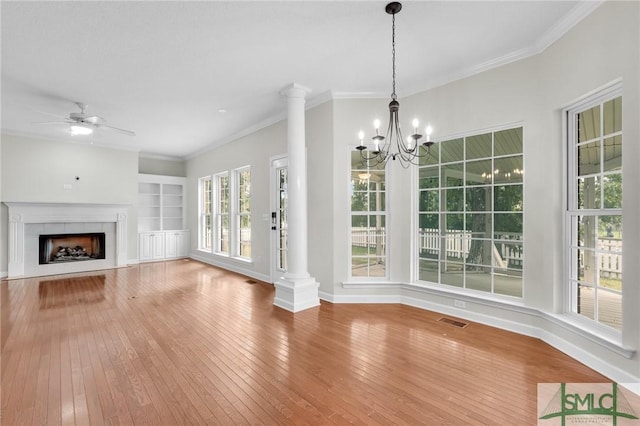 unfurnished living room with a tile fireplace, crown molding, ornate columns, and hardwood / wood-style floors