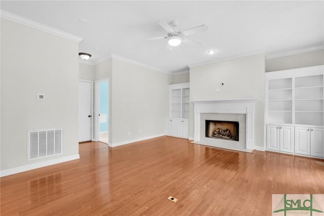 unfurnished living room featuring ornamental molding, a tile fireplace, and hardwood / wood-style floors