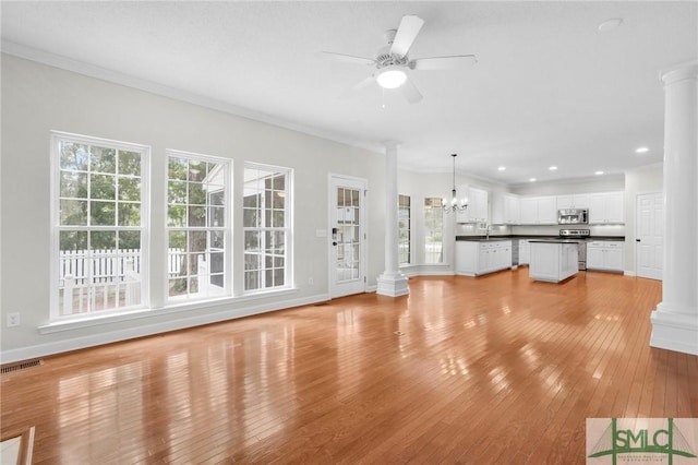 unfurnished living room with ornamental molding, ornate columns, and light hardwood / wood-style flooring