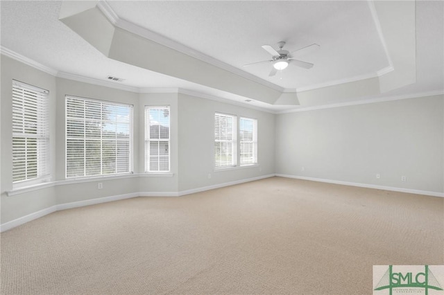 carpeted empty room featuring ceiling fan, ornamental molding, and a raised ceiling