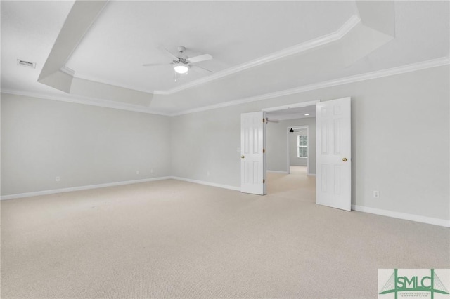 spare room with a raised ceiling, crown molding, ceiling fan, and light colored carpet