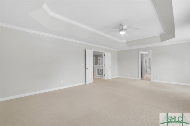 carpeted spare room featuring a raised ceiling, crown molding, and ceiling fan