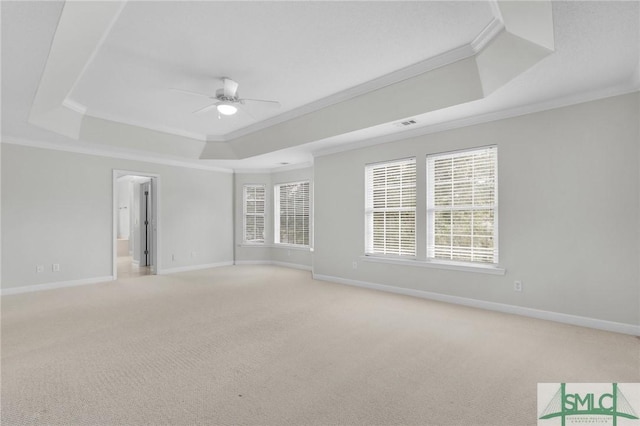 carpeted spare room with a raised ceiling, ceiling fan, and crown molding