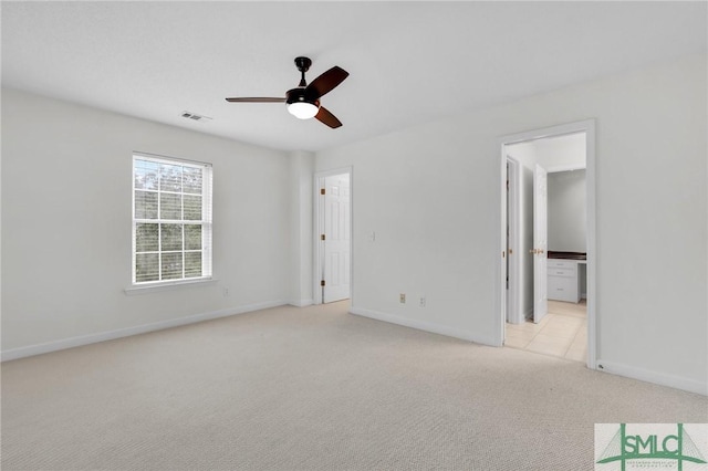 unfurnished bedroom with light carpet, ensuite bathroom, and ceiling fan