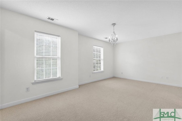 spare room with a chandelier and carpet flooring