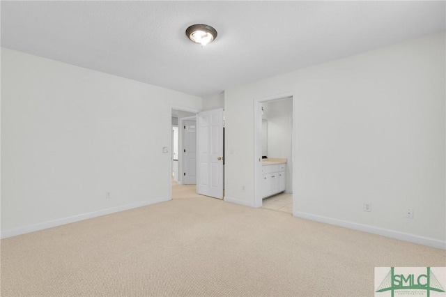 unfurnished bedroom featuring connected bathroom and light colored carpet