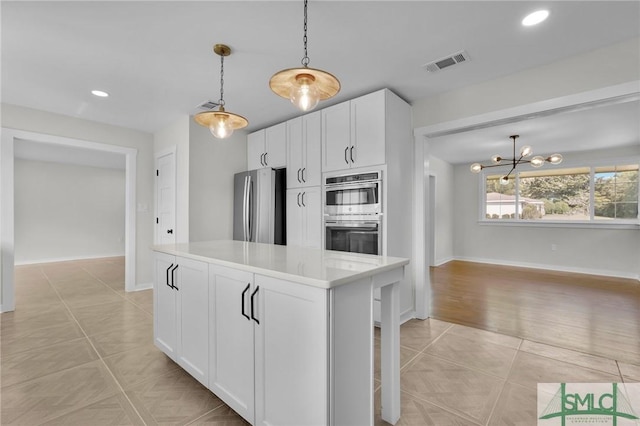 kitchen featuring appliances with stainless steel finishes, white cabinets, hanging light fixtures, a center island, and light tile patterned floors