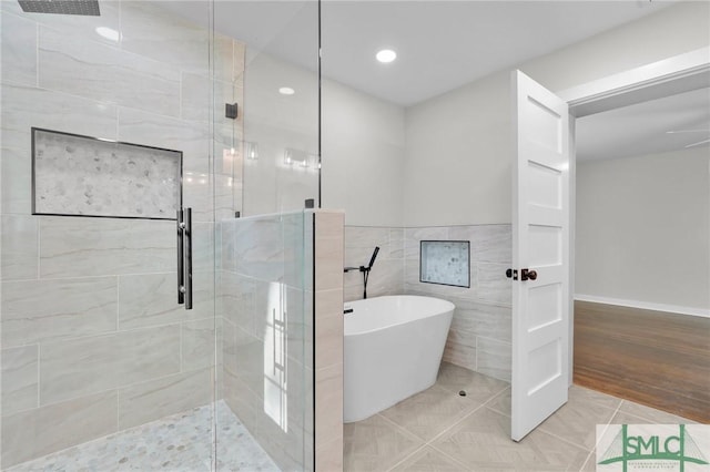 bathroom featuring separate shower and tub, tile walls, and tile patterned floors