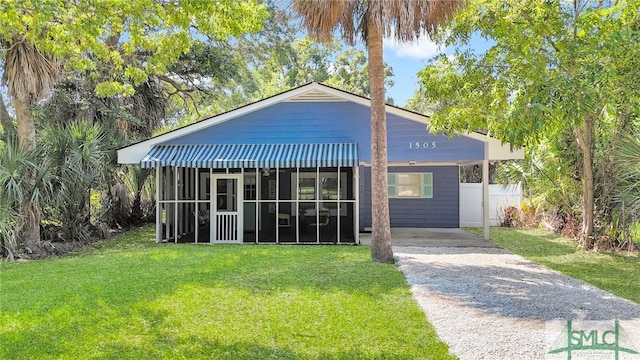 view of front of home with driveway, a front yard, and a sunroom