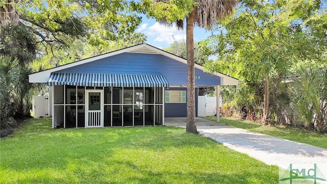 view of front of home with a front yard, fence, driveway, and a sunroom