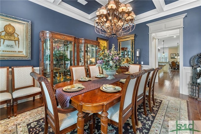 dining space featuring coffered ceiling, ornamental molding, hardwood / wood-style flooring, wainscoting, and a chandelier