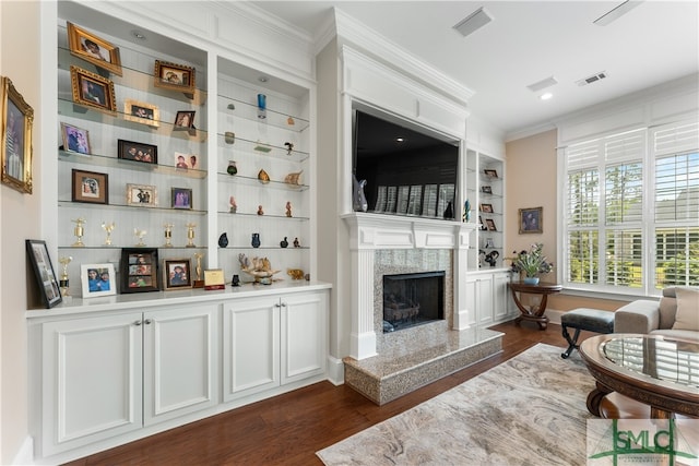 living room with a fireplace, ornamental molding, dark hardwood / wood-style flooring, and built in shelves