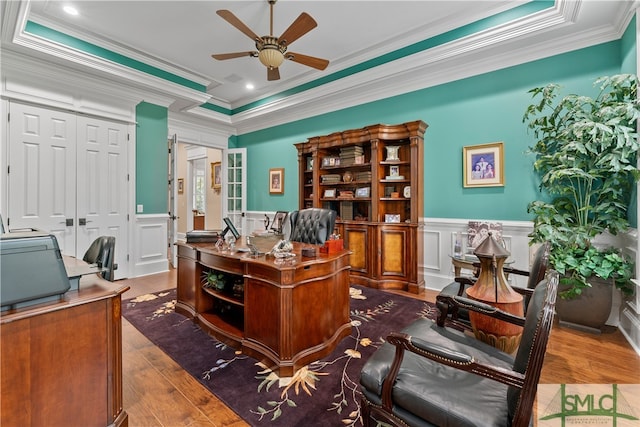 office featuring a tray ceiling, ceiling fan, ornamental molding, and wood-type flooring