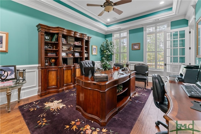 office space featuring hardwood / wood-style floors, a raised ceiling, crown molding, and ceiling fan