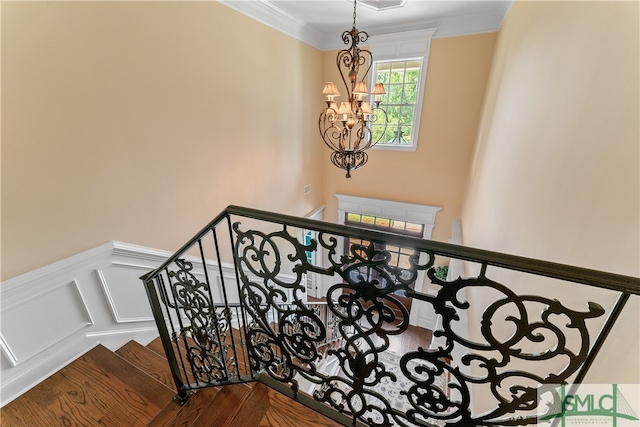 stairs with an inviting chandelier, hardwood / wood-style floors, and ornamental molding