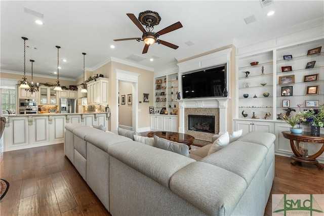 living area with ornamental molding, a ceiling fan, dark wood-style floors, recessed lighting, and a premium fireplace