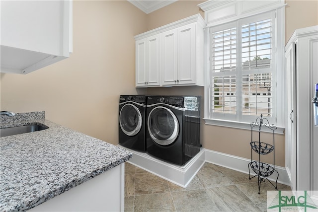 washroom featuring washing machine and dryer, crown molding, plenty of natural light, and cabinets