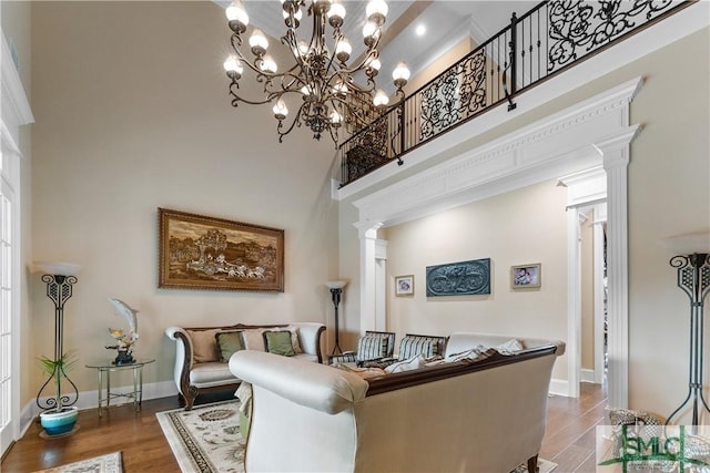 living room featuring decorative columns, baseboards, wood finished floors, and a towering ceiling