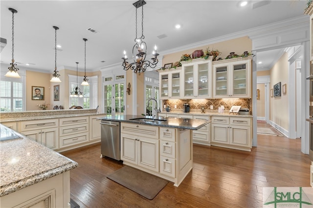 kitchen featuring hanging light fixtures, an island with sink, dishwasher, cream cabinets, and hardwood / wood-style flooring