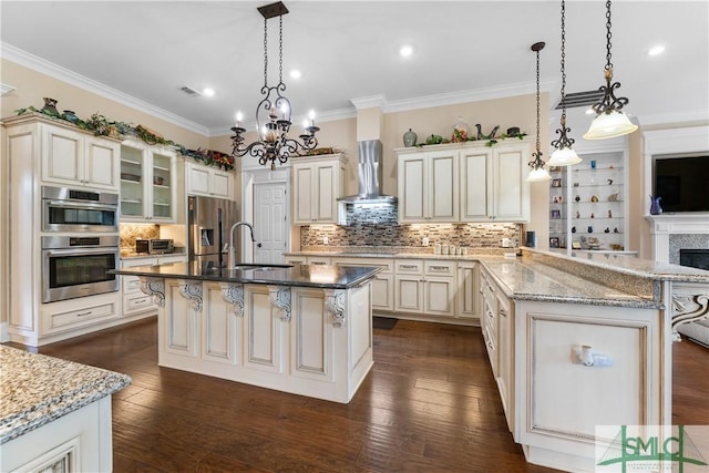 kitchen with a kitchen bar, ornamental molding, appliances with stainless steel finishes, wall chimney exhaust hood, and a sink