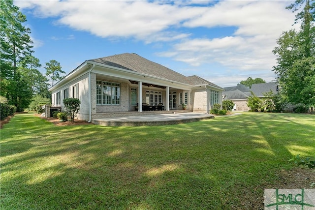 back of house featuring brick siding, a lawn, and a patio area