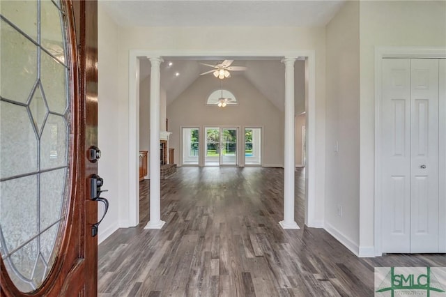 entrance foyer with dark wood-type flooring, ornate columns, vaulted ceiling, ceiling fan, and a fireplace