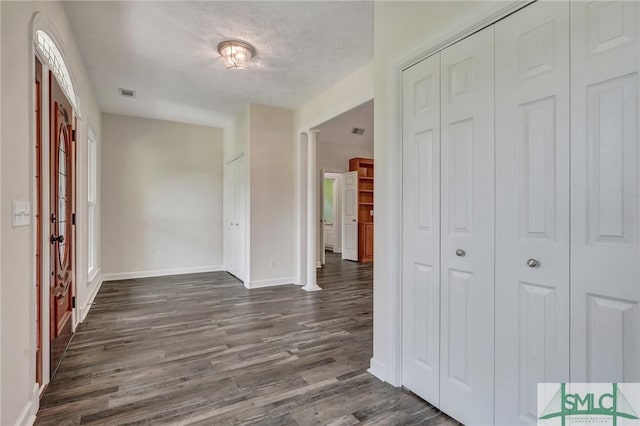 entryway featuring ornate columns, a textured ceiling, and dark hardwood / wood-style flooring