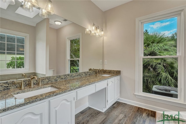 bathroom with a notable chandelier, dual bowl vanity, hardwood / wood-style flooring, and a healthy amount of sunlight