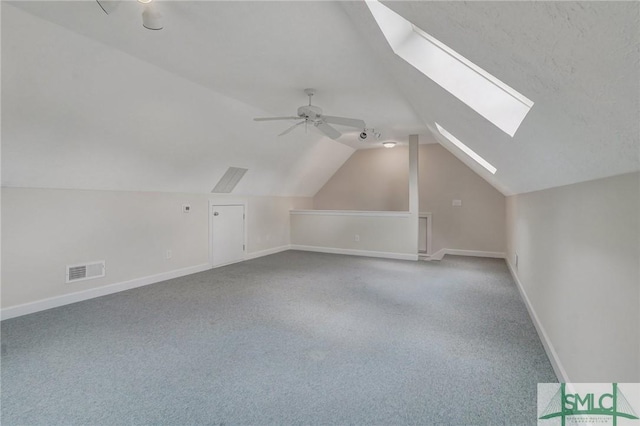 additional living space with light carpet, ceiling fan, and vaulted ceiling with skylight