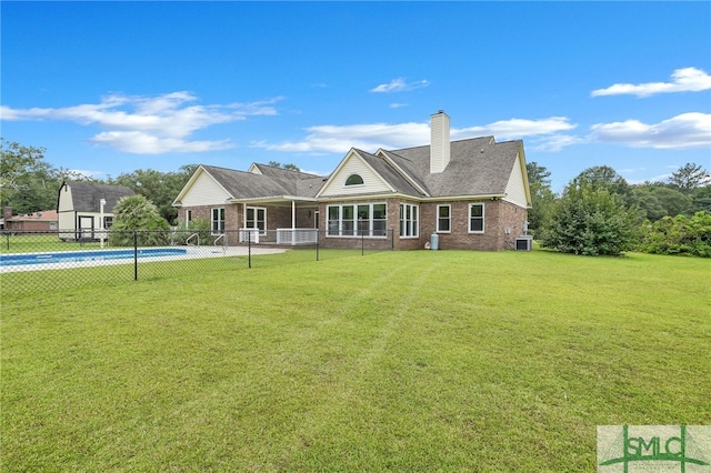 back of house with a fenced in pool and a lawn