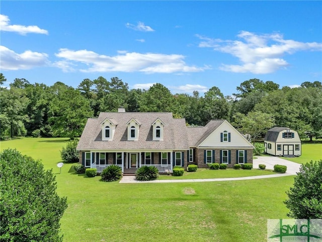 cape cod home with an outbuilding, covered porch, and a front lawn