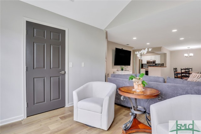 living room featuring lofted ceiling, a chandelier, and light hardwood / wood-style floors