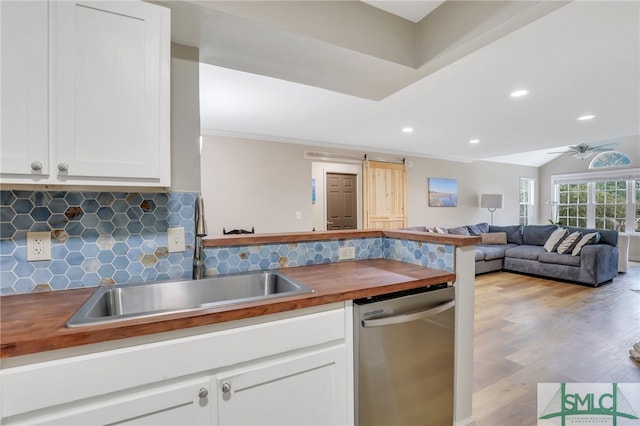 kitchen featuring ceiling fan, sink, tasteful backsplash, stainless steel dishwasher, and light hardwood / wood-style flooring