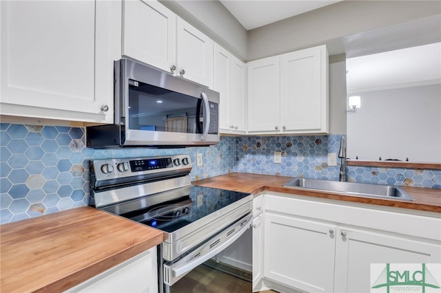 kitchen featuring tasteful backsplash, appliances with stainless steel finishes, white cabinets, sink, and butcher block countertops