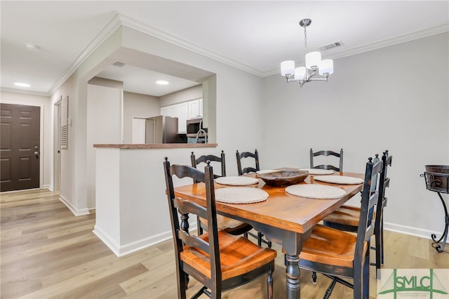 dining room featuring light hardwood / wood-style flooring, crown molding, and an inviting chandelier