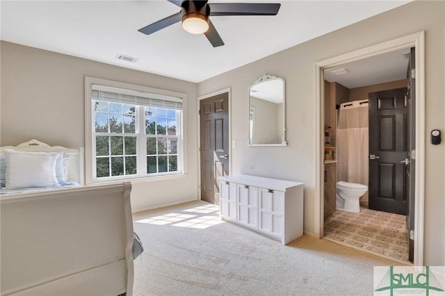 bedroom featuring ensuite bathroom, light carpet, and ceiling fan